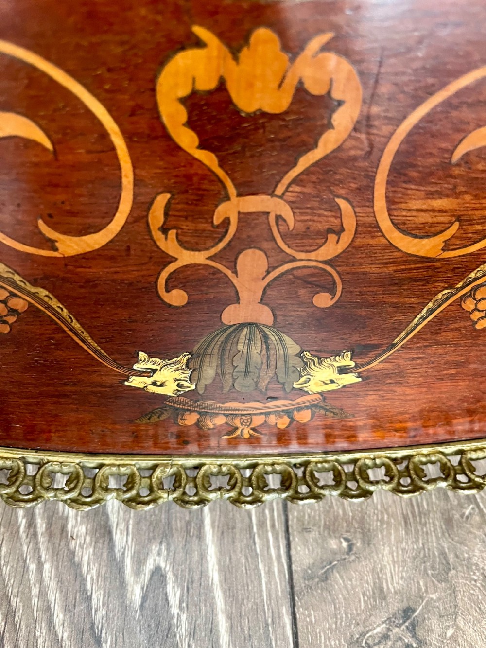 An oval wooden Edwardian serving tray featuring detailed marquetry inlay of scrollwork and cherubs with two brass side handles and a metal rim. View IV