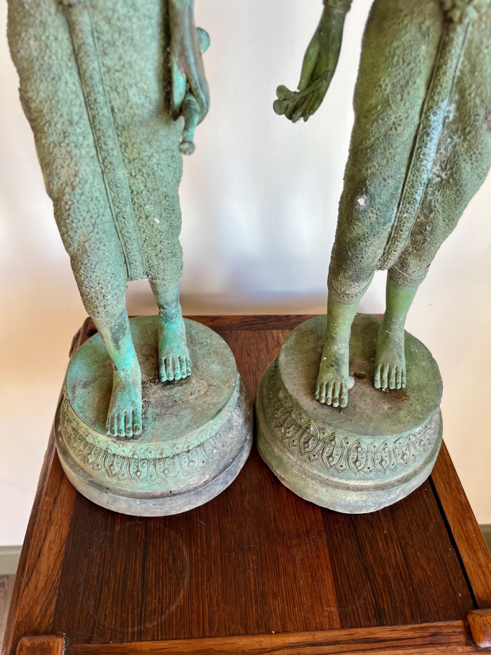 A pair of full-length bronze statues depicting a standing male and female figure with a green verdigris patina, positioned on rounded carved bases. View IV