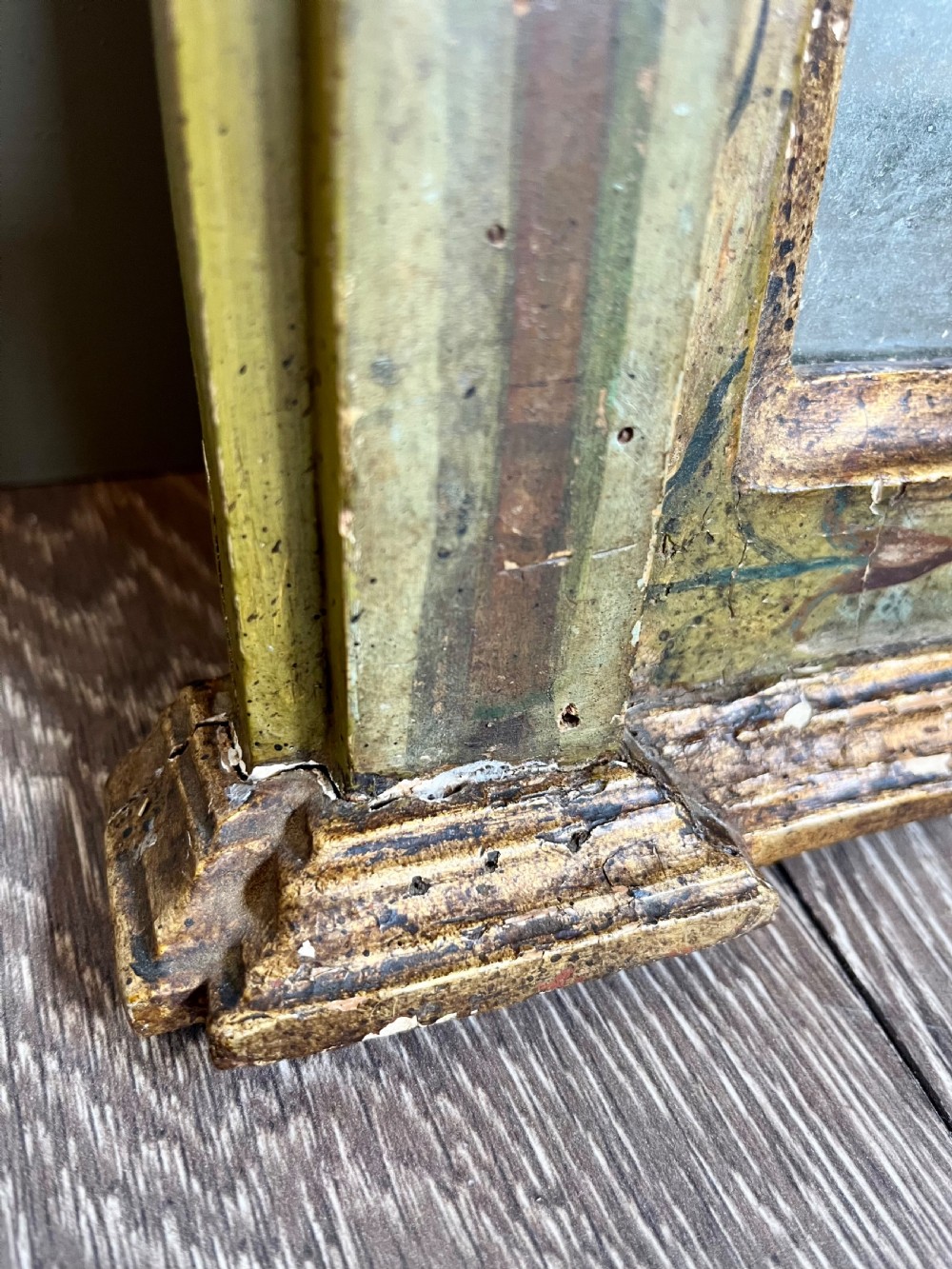 A rectangular painted wooden wall mirror featuring a carved scrolled pediment, an arched inner frame, and painted foliage motifs on a green background. View IV