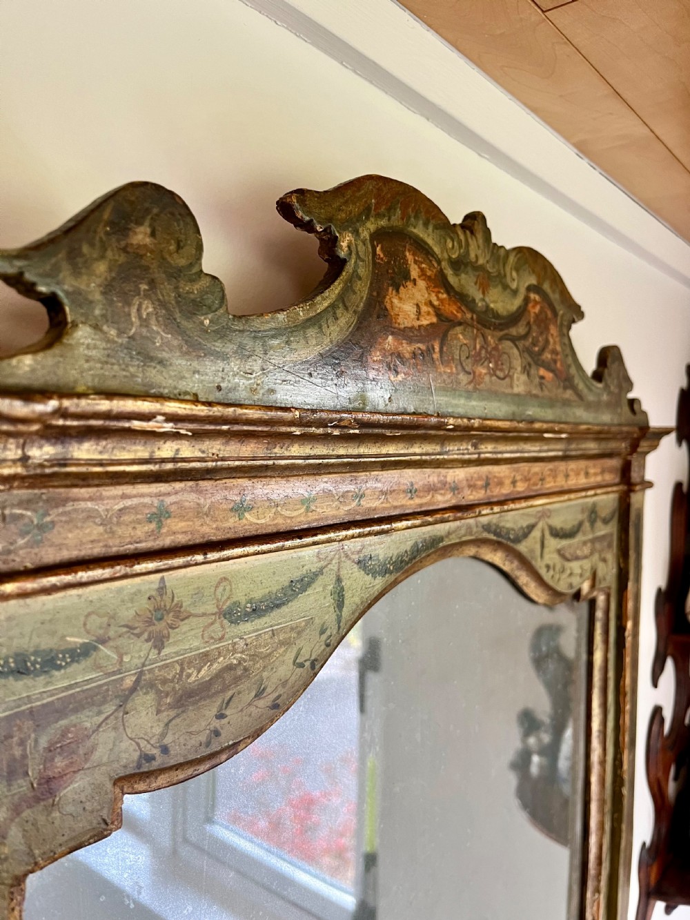 A rectangular painted wooden wall mirror featuring a carved scrolled pediment, an arched inner frame, and painted foliage motifs on a green background. View XII