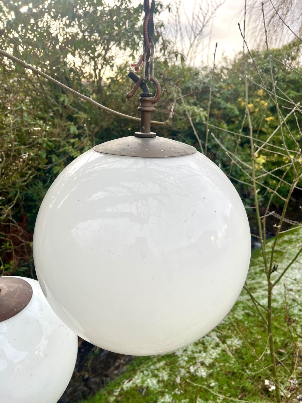 A set of three large white spherical opaline glass globe pendant lights suspended from dark metal chains. View IV