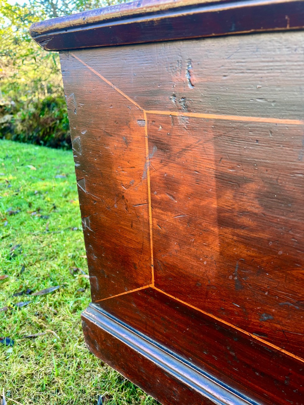 A rectangular dark reddish-brown pine storage chest with a hinged lid, painted panel border detail, and iron side handles. View IV