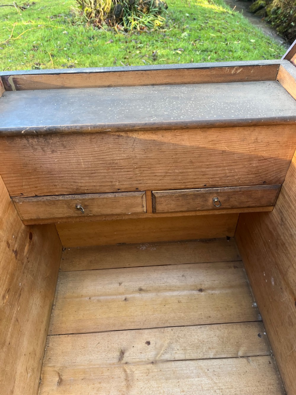A rectangular dark reddish-brown pine storage chest with a hinged lid, painted panel border detail, and iron side handles. View X