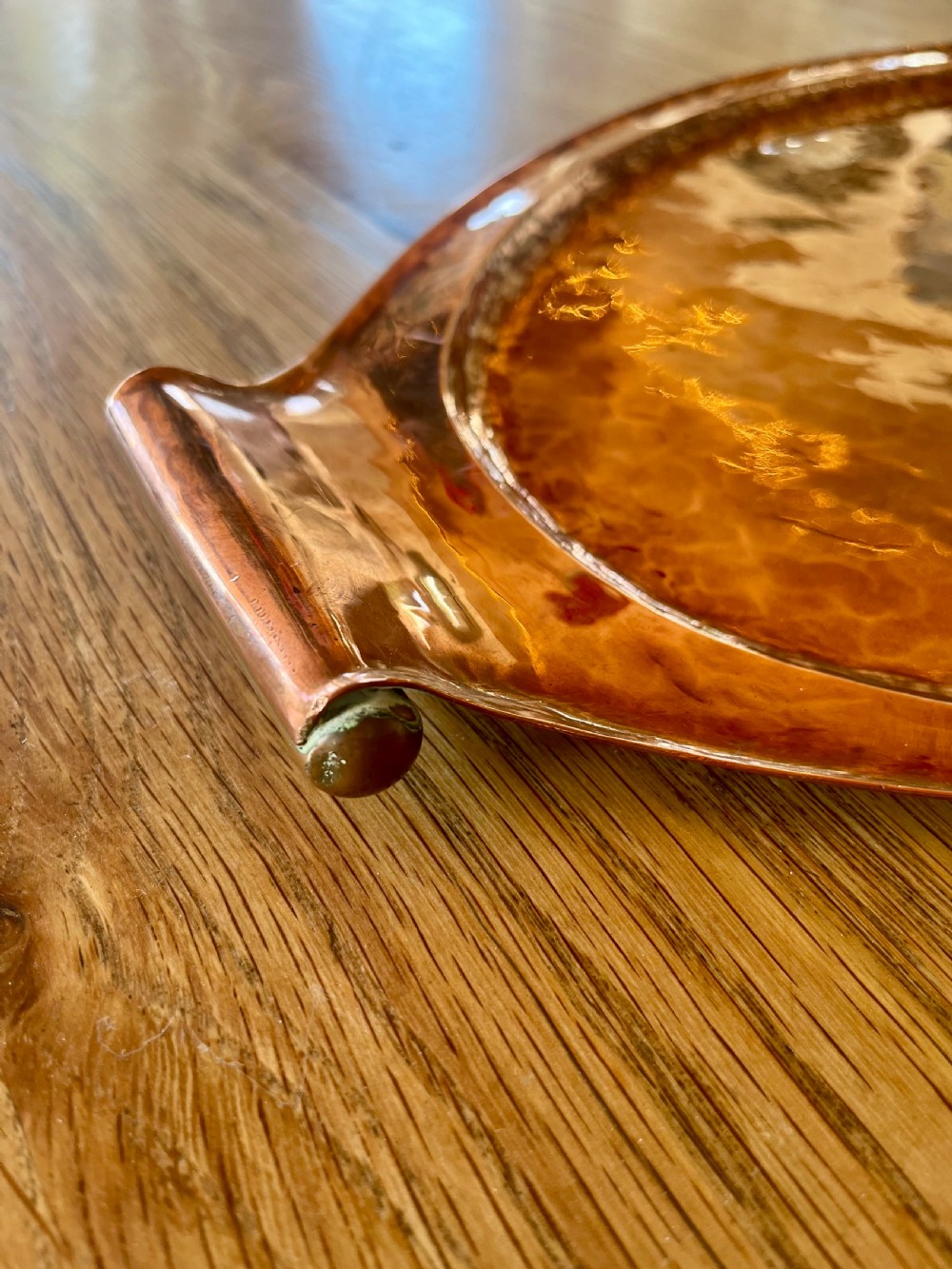 A large oval hand-hammered copper serving tray featuring integrated raised handles at both ends. View II