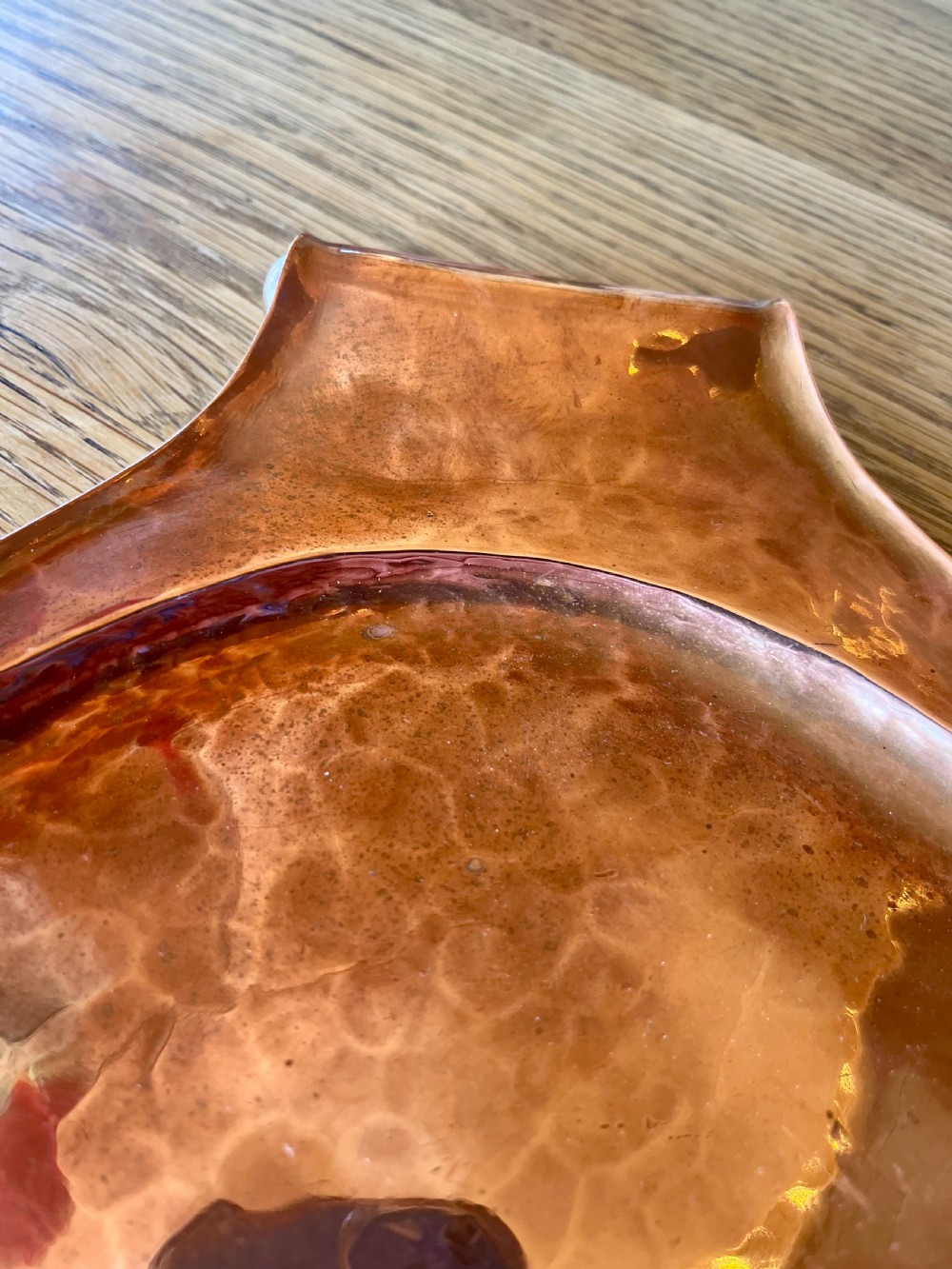A large oval hand-hammered copper serving tray featuring integrated raised handles at both ends. View V