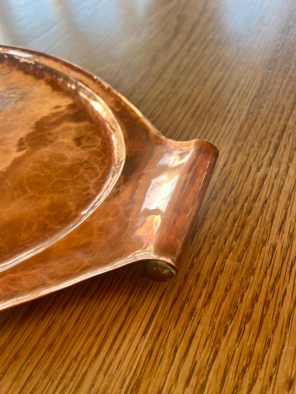 A large oval hand-hammered copper serving tray featuring integrated raised handles at both ends. View IX