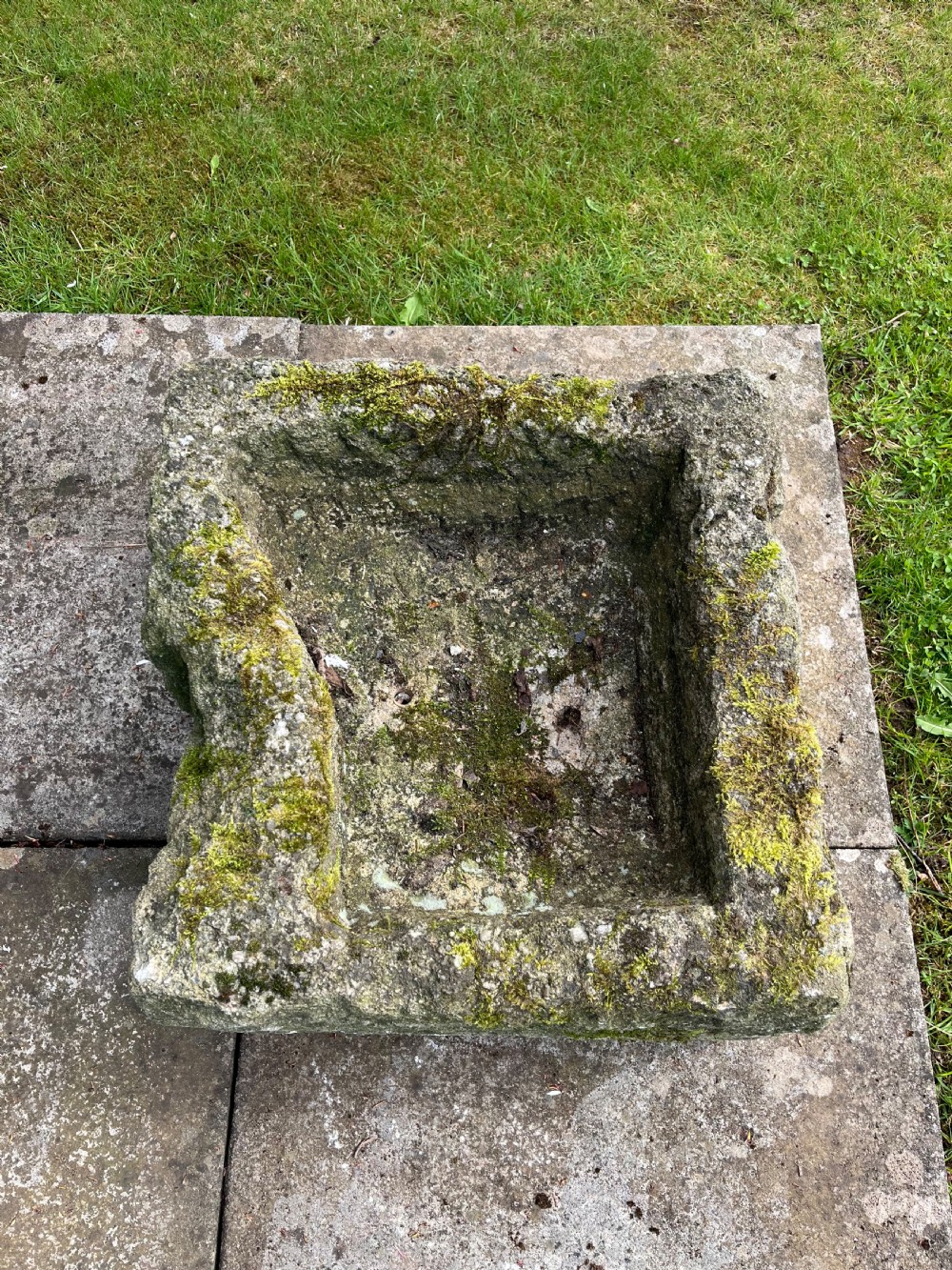 A rectangular hand-carved grey stone garden trough with a moss-covered weathered surface and a hollowed-out central basin. View IV