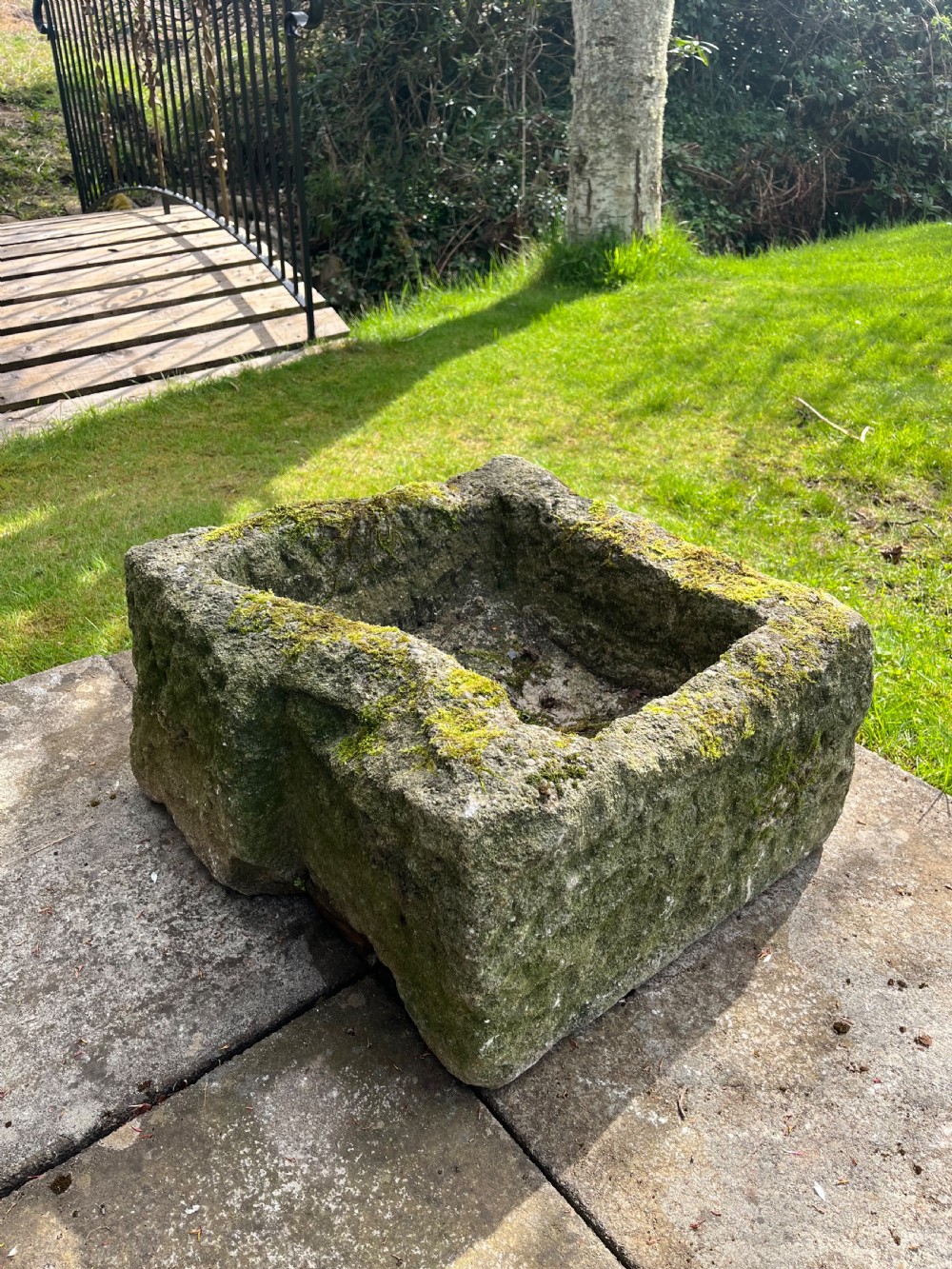 A rectangular hand-carved grey stone garden trough with a moss-covered weathered surface and a hollowed-out central basin. View VII