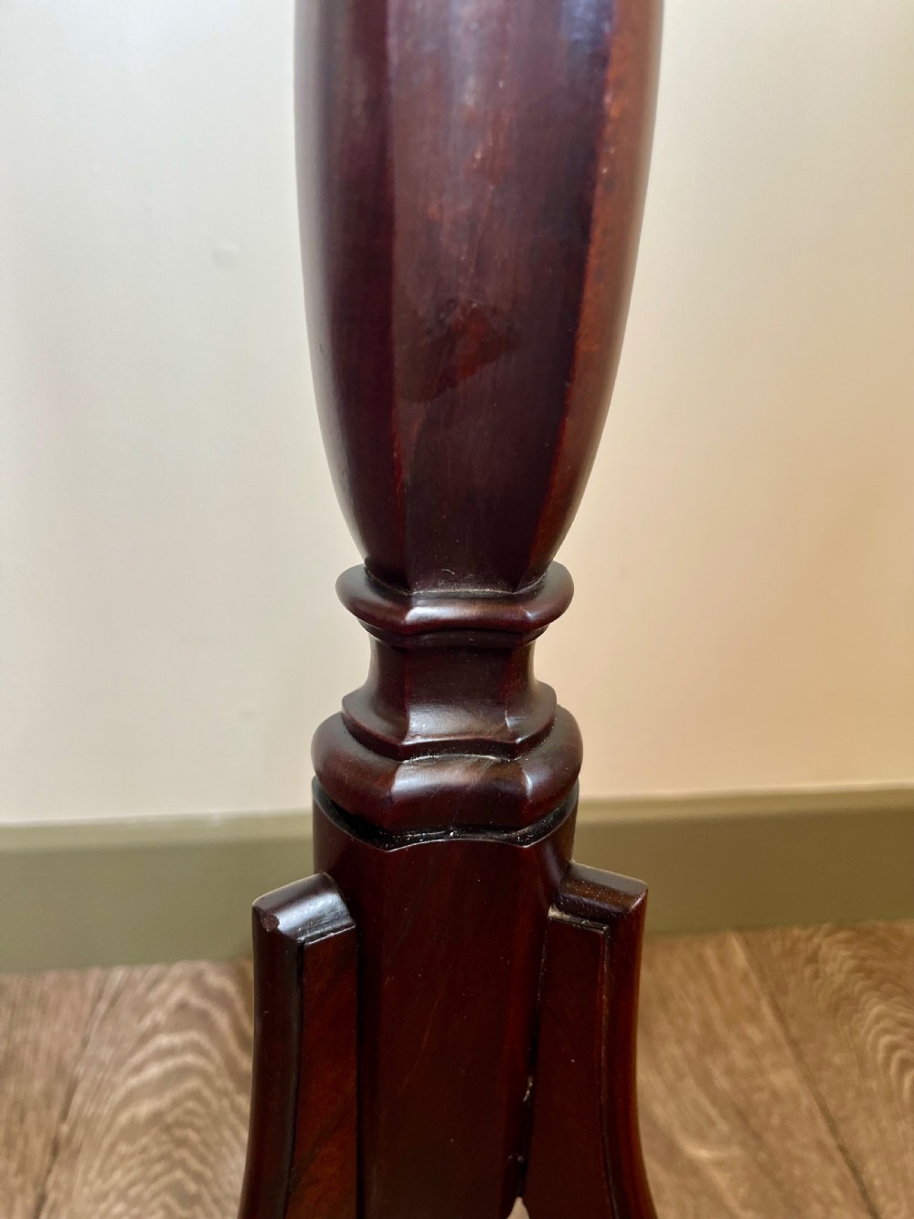 A dark mahogany torchere plant stand featuring a scalloped circular top, a turned column shaft, and a tripod base with scrolled feet. View V