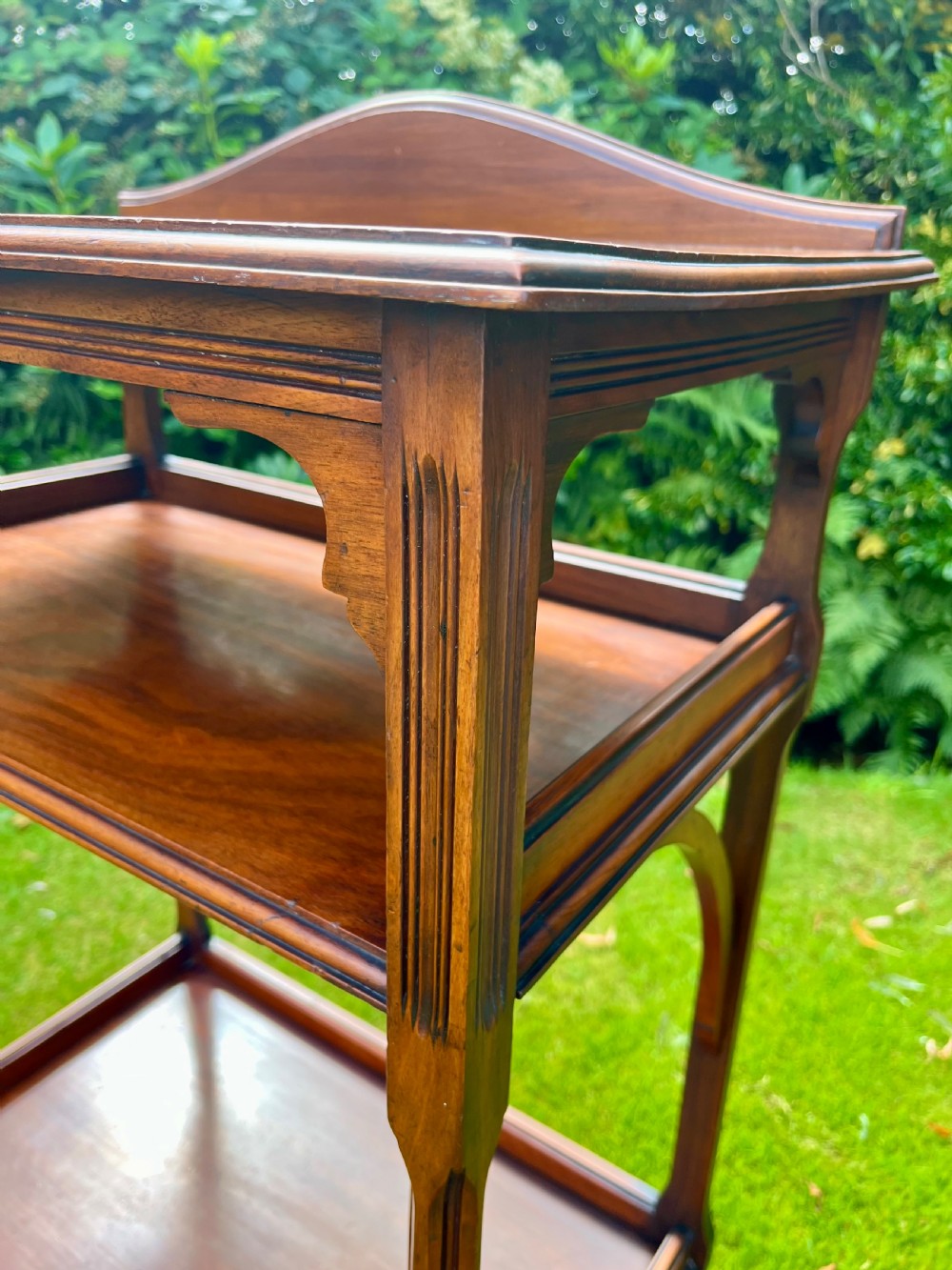 A three-tiered walnut wooden console table featuring a shaped gallery top, carved aprons, and slender tapered legs. View II