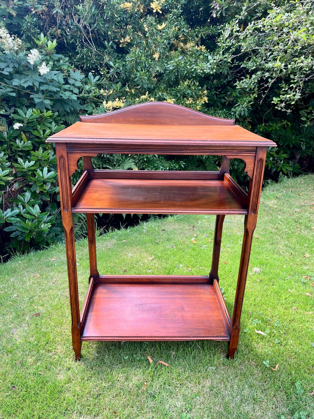 A three-tiered walnut wooden console table featuring a shaped gallery top, carved aprons, and slender tapered legs. View IV
