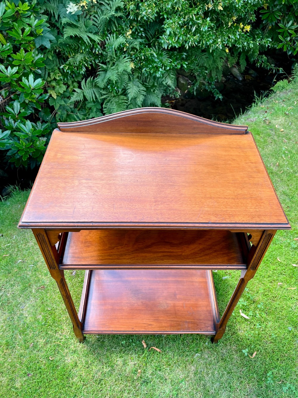 A three-tiered walnut wooden console table featuring a shaped gallery top, carved aprons, and slender tapered legs. View V