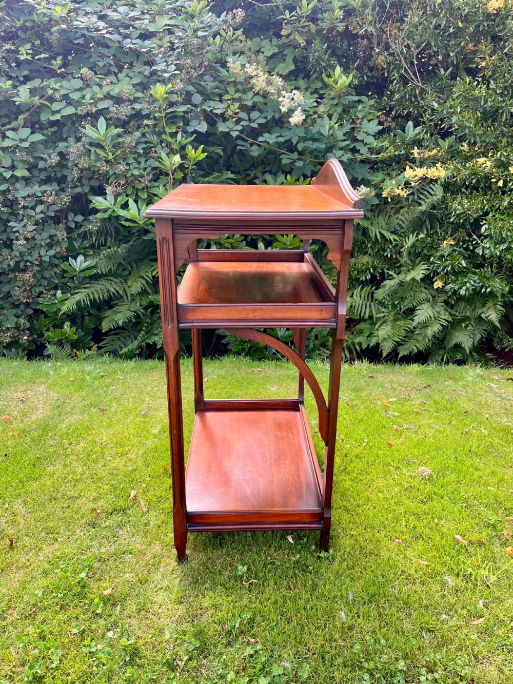 A three-tiered walnut wooden console table featuring a shaped gallery top, carved aprons, and slender tapered legs. View VI