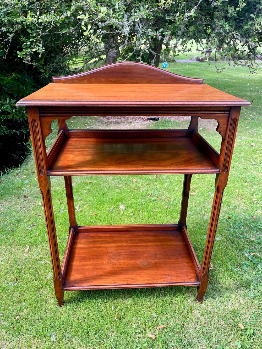 A three-tiered walnut wooden console table featuring a shaped gallery top, carved aprons, and slender tapered legs. View VIII