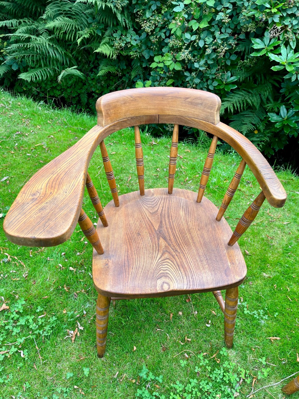 A pair of warm brown wooden smokers bow armchairs with turned spindles, contoured saddle seats, and turned legs. View II