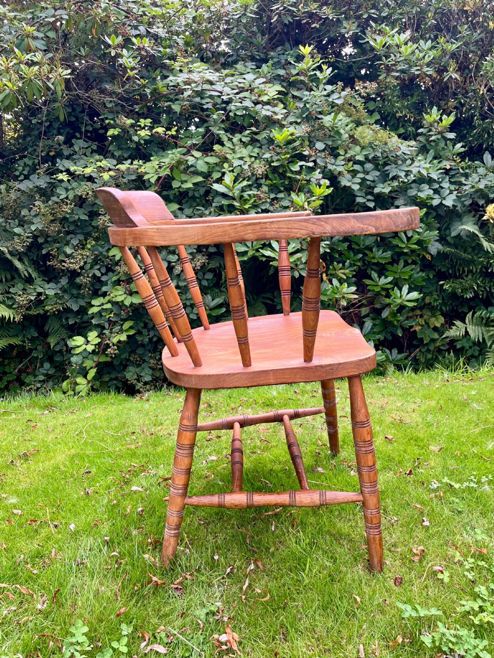 A pair of warm brown wooden smokers bow armchairs with turned spindles, contoured saddle seats, and turned legs. View IV