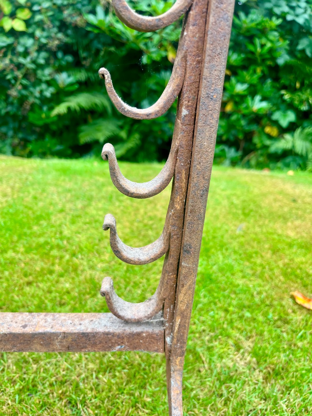 A pair of hand-forged wrought iron andirons featuring vertical spit hooks, arched feet, and conical brass finials. View III