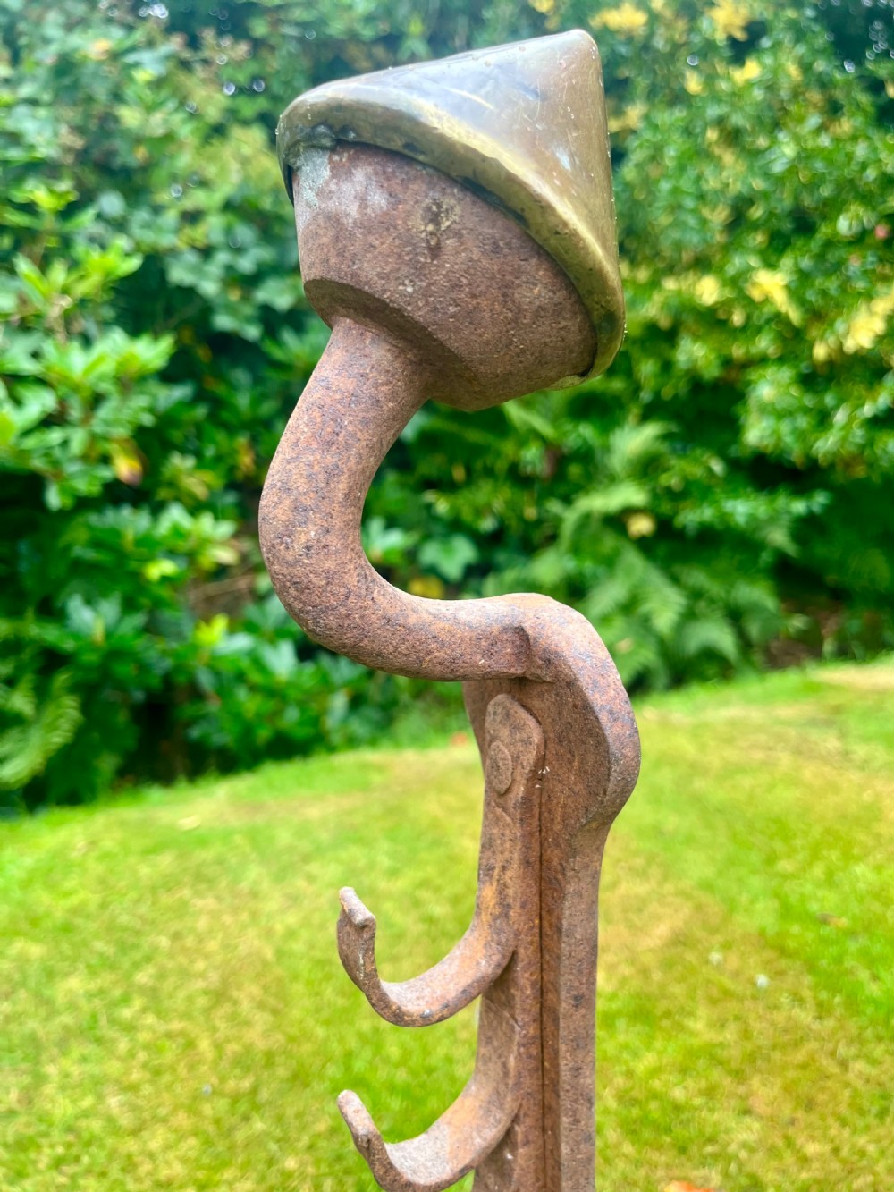 A pair of hand-forged wrought iron andirons featuring vertical spit hooks, arched feet, and conical brass finials. View IV