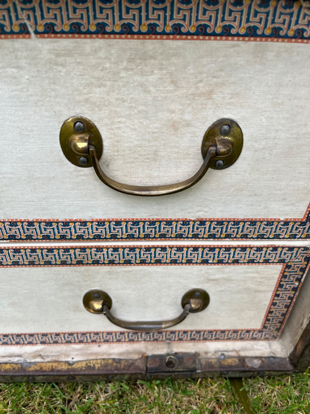 A rectangular antique dark brown canvas travel trunk featuring metal corner brackets, studding along the edges, and stencilled initials on top. View IX