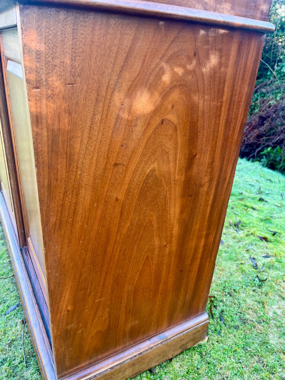 A two-part warm brown mahogany campaign cabinet featuring four panelled sliding doors with flush-fitting brass pull handles. View VI