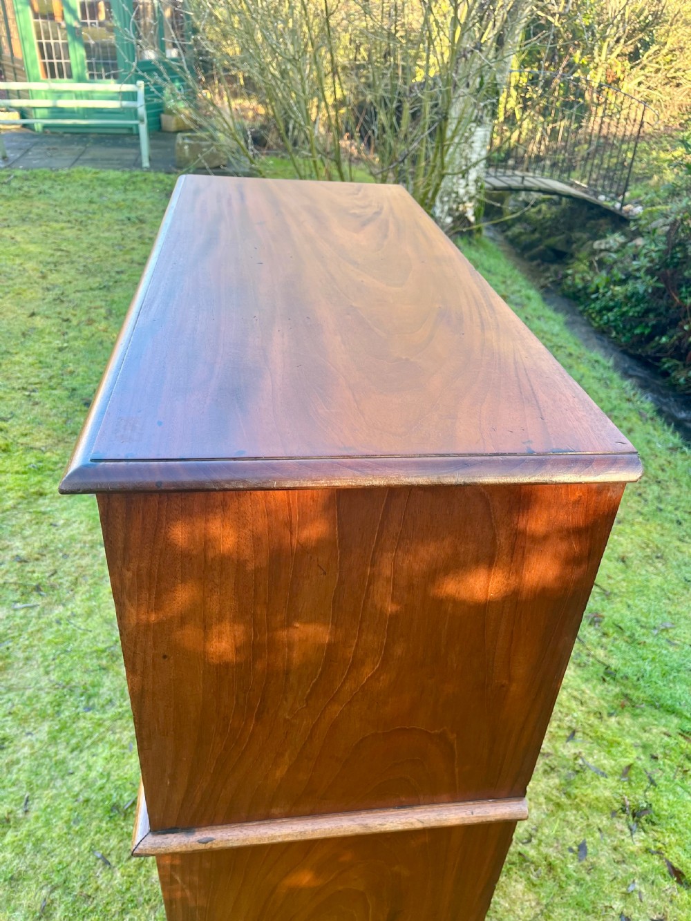 A two-part warm brown mahogany campaign cabinet featuring four panelled sliding doors with flush-fitting brass pull handles. View VII