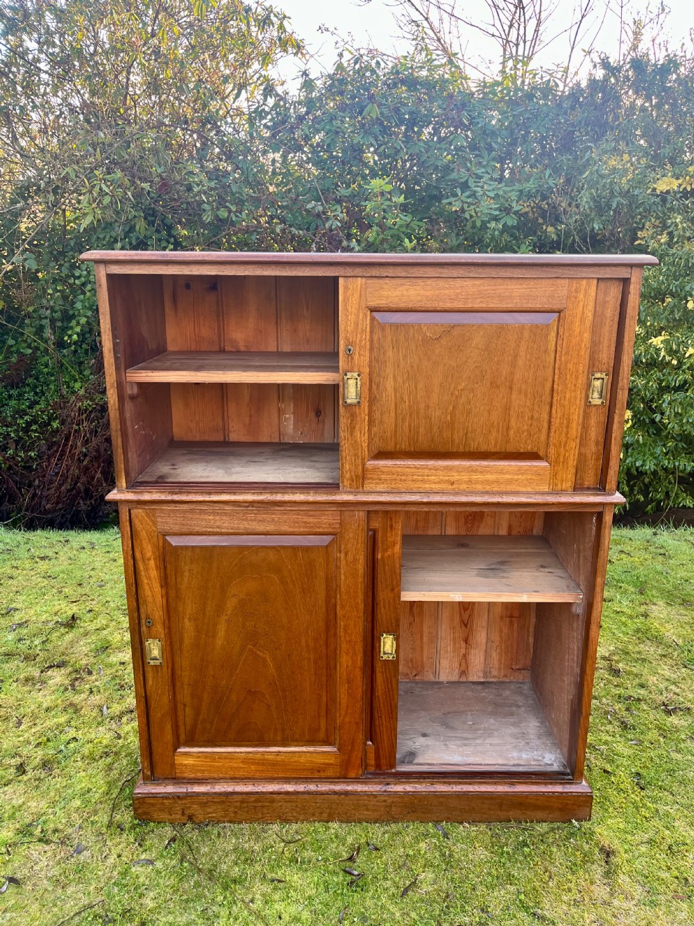 A two-part warm brown mahogany campaign cabinet featuring four panelled sliding doors with flush-fitting brass pull handles. View IX