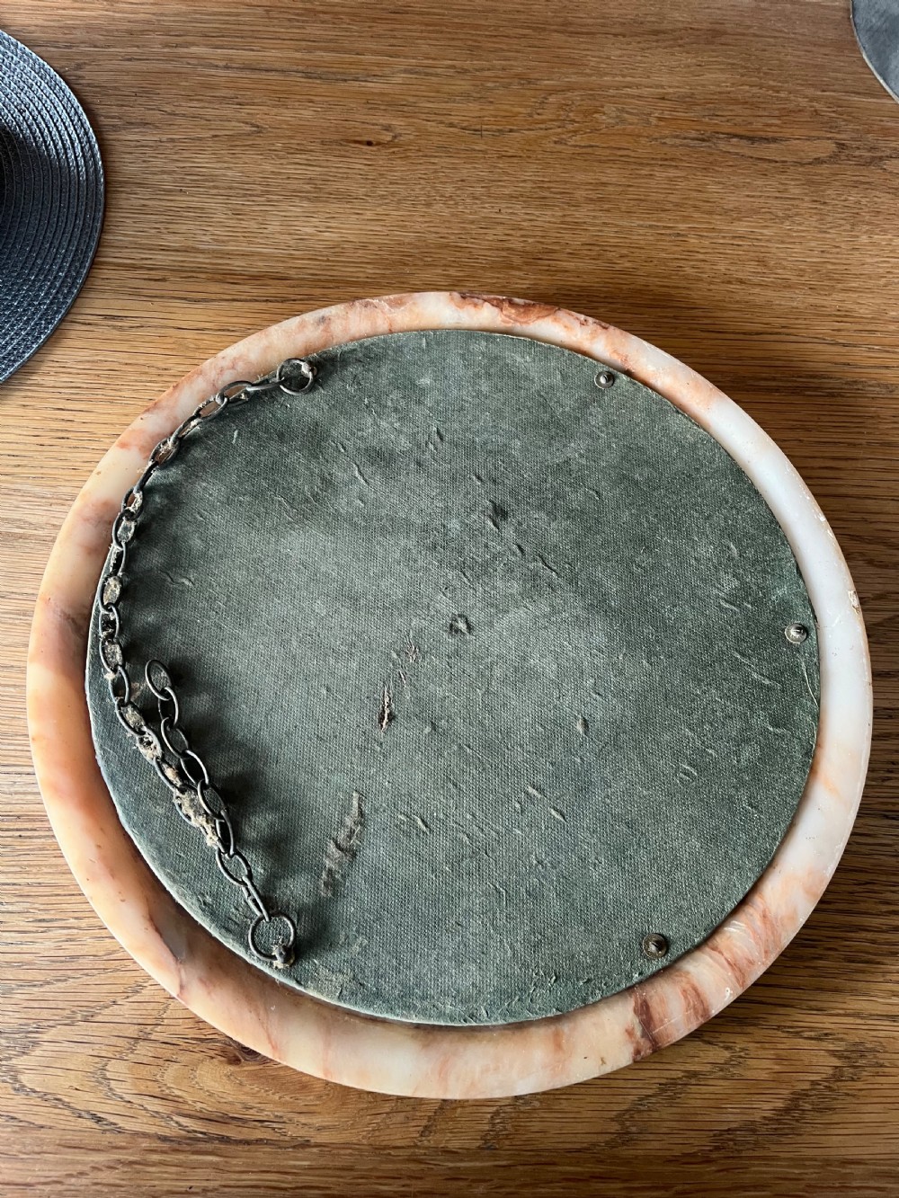 A circular wall mirror featuring a thick alabaster stone frame with visible pink and cream veining surrounding bevelled mirror glass. View V