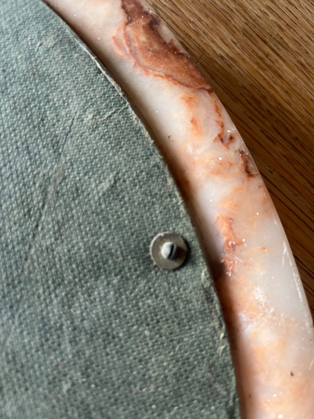 A circular wall mirror featuring a thick alabaster stone frame with visible pink and cream veining surrounding bevelled mirror glass. View VII
