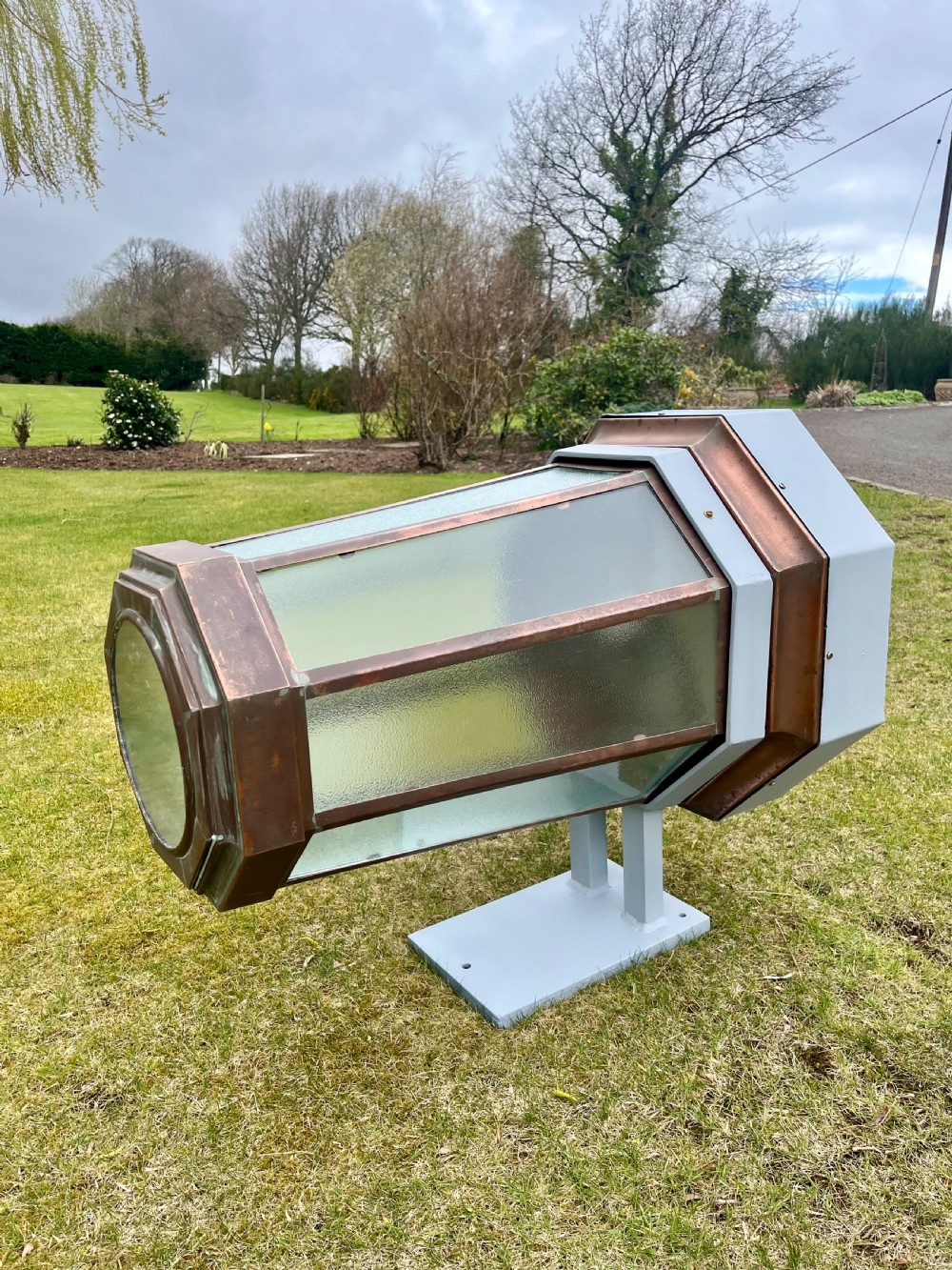 A large octagonal copper wall lantern with textured glass panels mounted on a grey metal bracket.