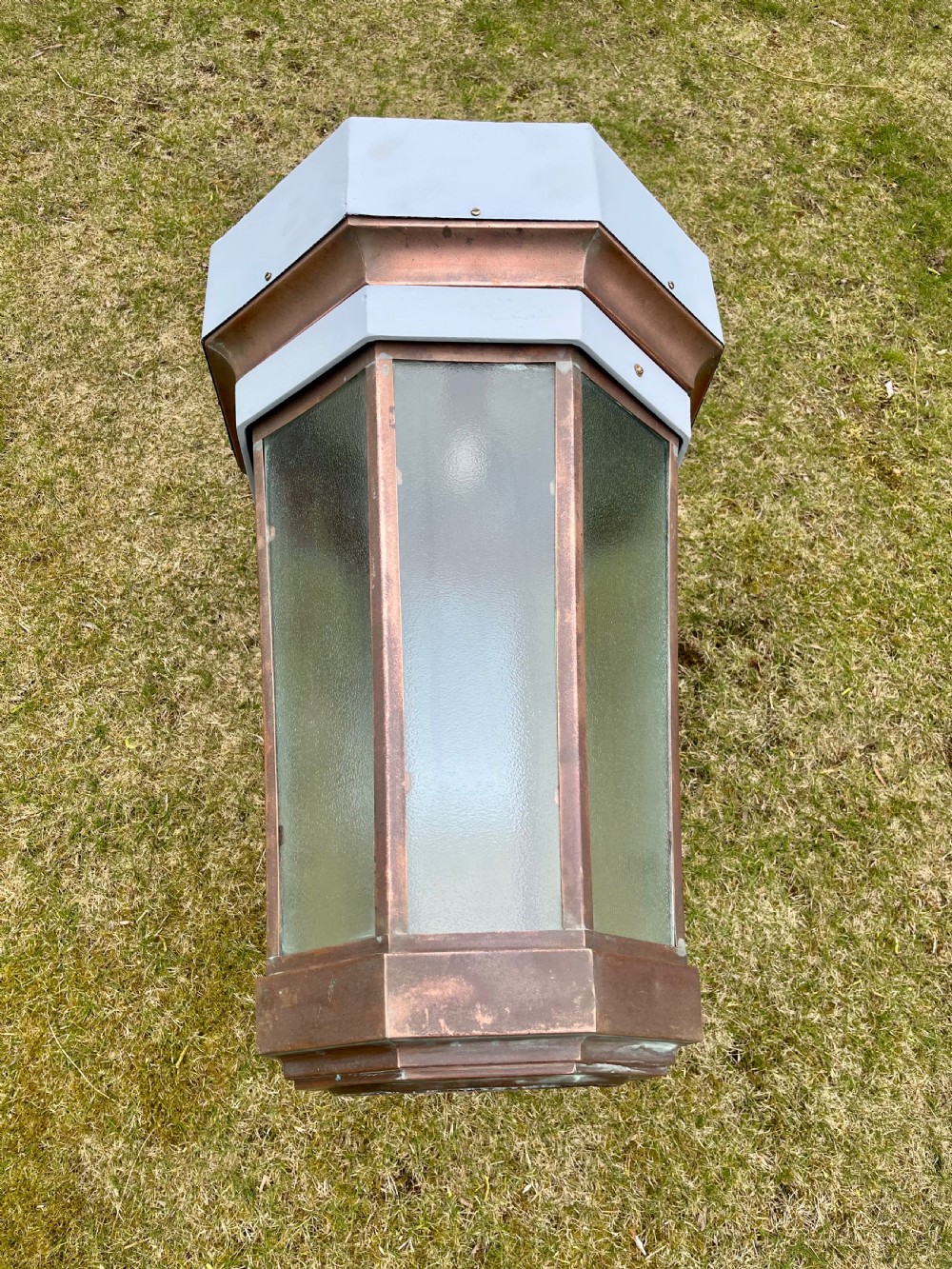 A large octagonal copper wall lantern with textured glass panels mounted on a grey metal bracket. View II