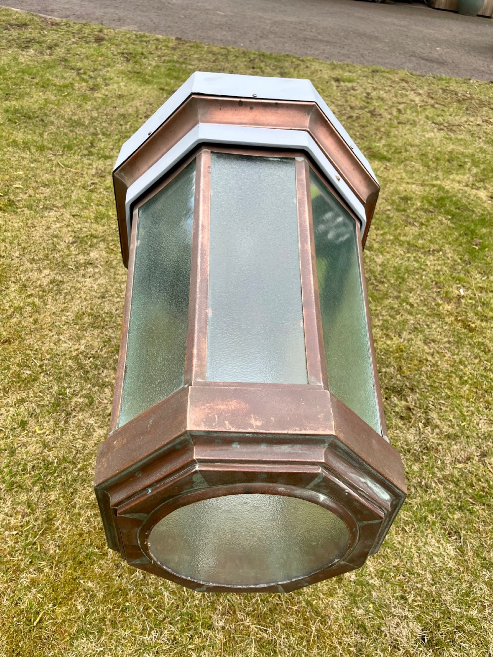 A large octagonal copper wall lantern with textured glass panels mounted on a grey metal bracket. View III