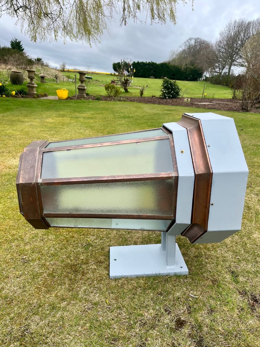 A large octagonal copper wall lantern with textured glass panels mounted on a grey metal bracket. View IV
