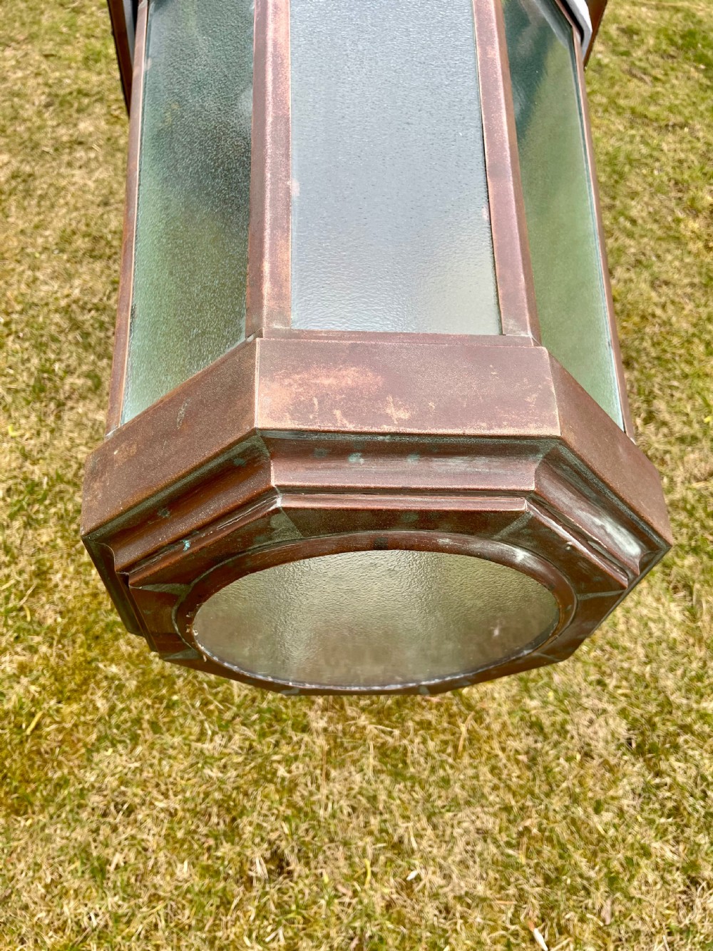 A large octagonal copper wall lantern with textured glass panels mounted on a grey metal bracket. View VII
