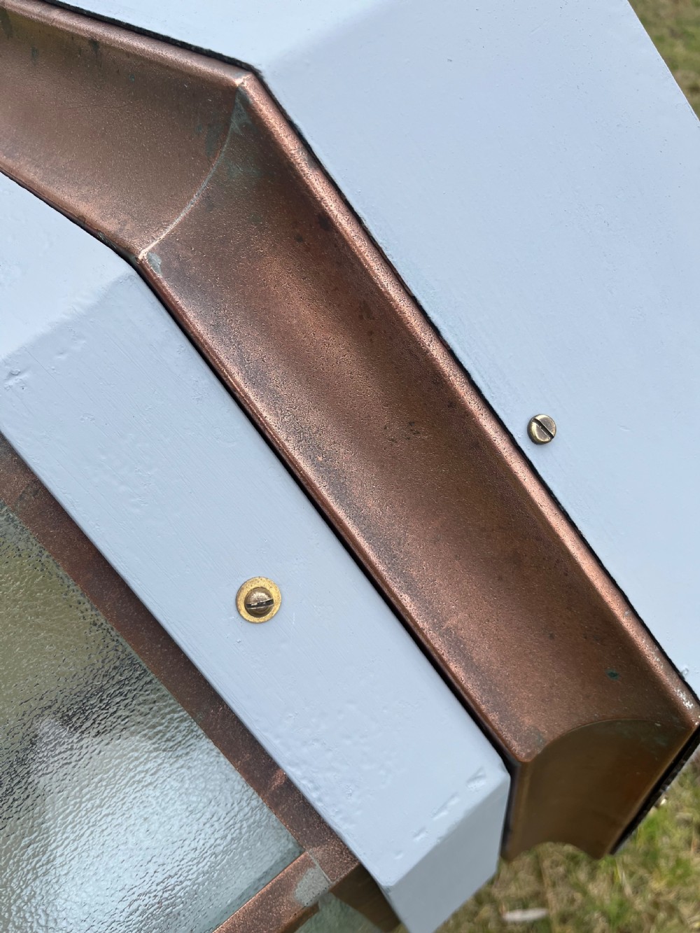 A large octagonal copper wall lantern with textured glass panels mounted on a grey metal bracket. View VIII
