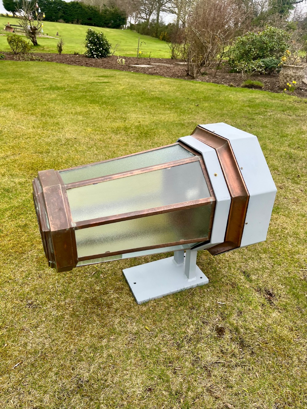 A large octagonal copper wall lantern with textured glass panels mounted on a grey metal bracket. View XI