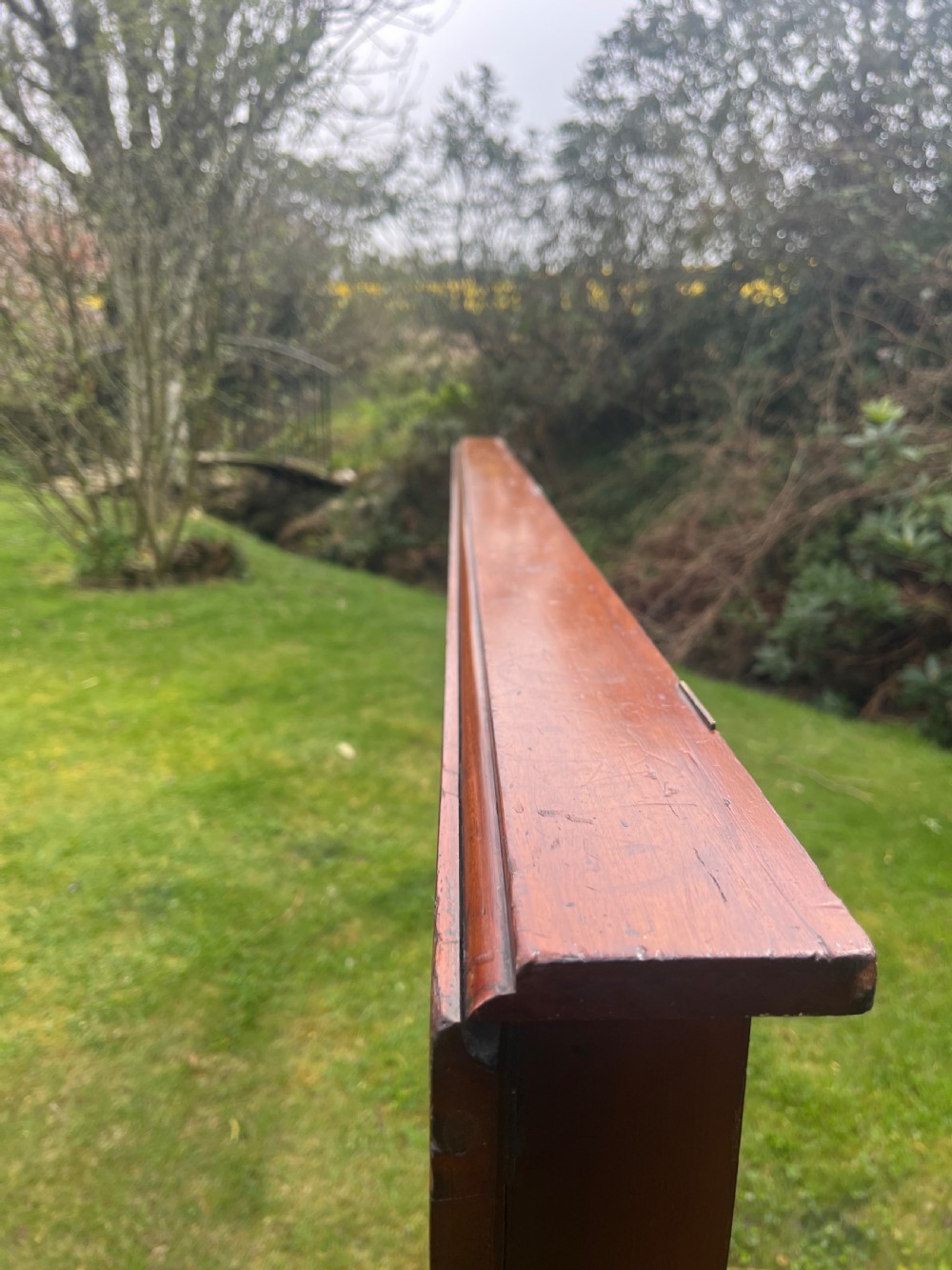 A long, narrow antique wooden butlers console table with a polished warm brown finish, rounded corners, and a collapsible trestle leg frame. View III