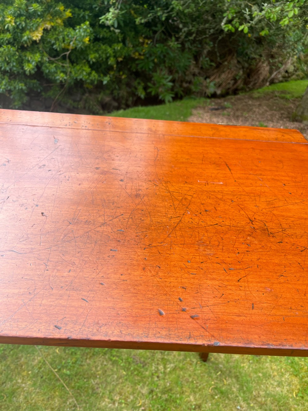A long, narrow antique wooden butlers console table with a polished warm brown finish, rounded corners, and a collapsible trestle leg frame. View X