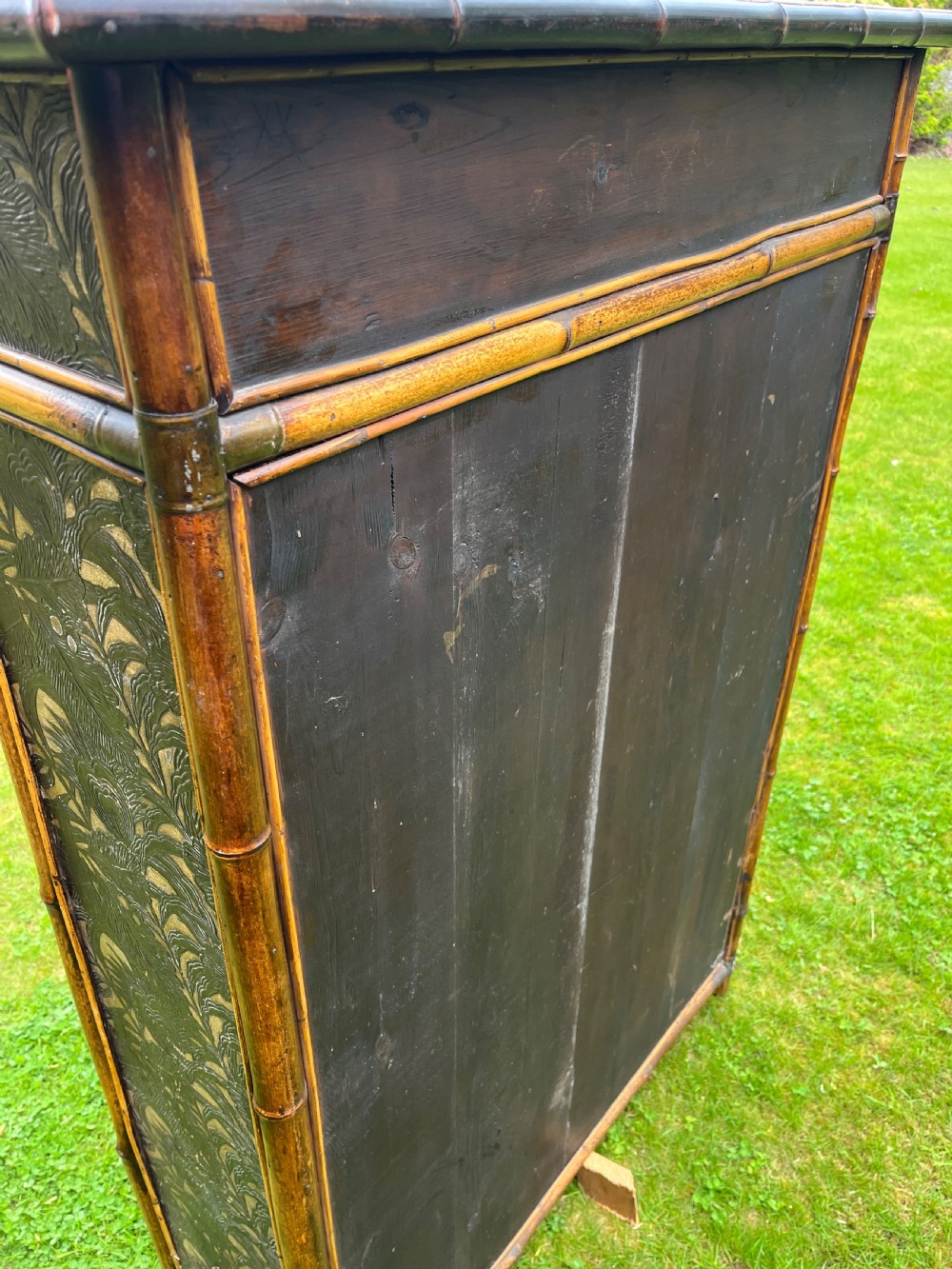 A late Victorian bamboo display cabinet with two glazed doors, upper drawers, and dark embossed botanical pattern panels. View VI
