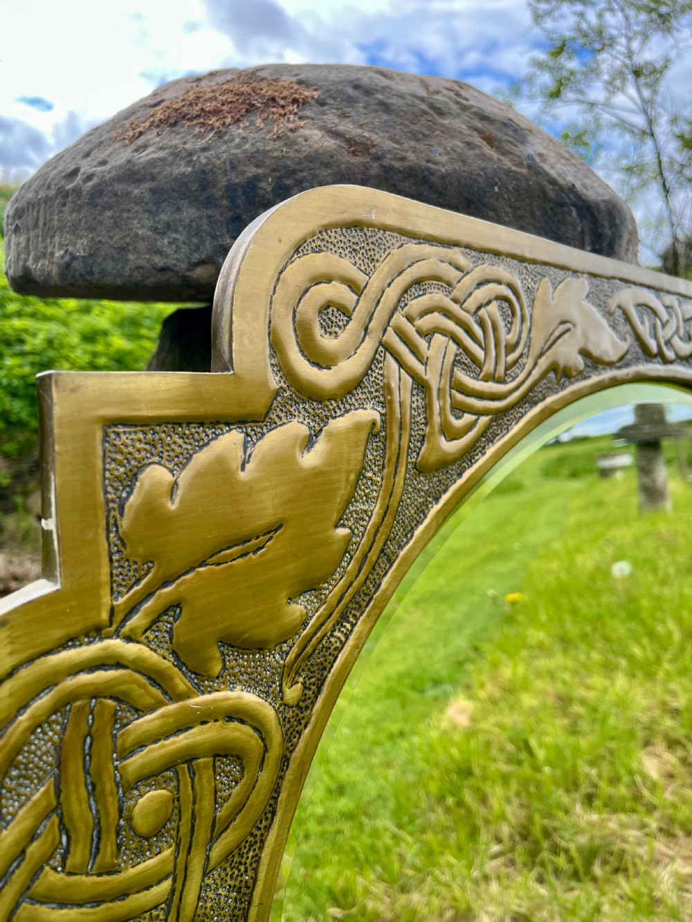 A large shaped brass wall mirror featuring an oval glass centre enclosed by relief Celtic knotwork and leaf motifs. View VII