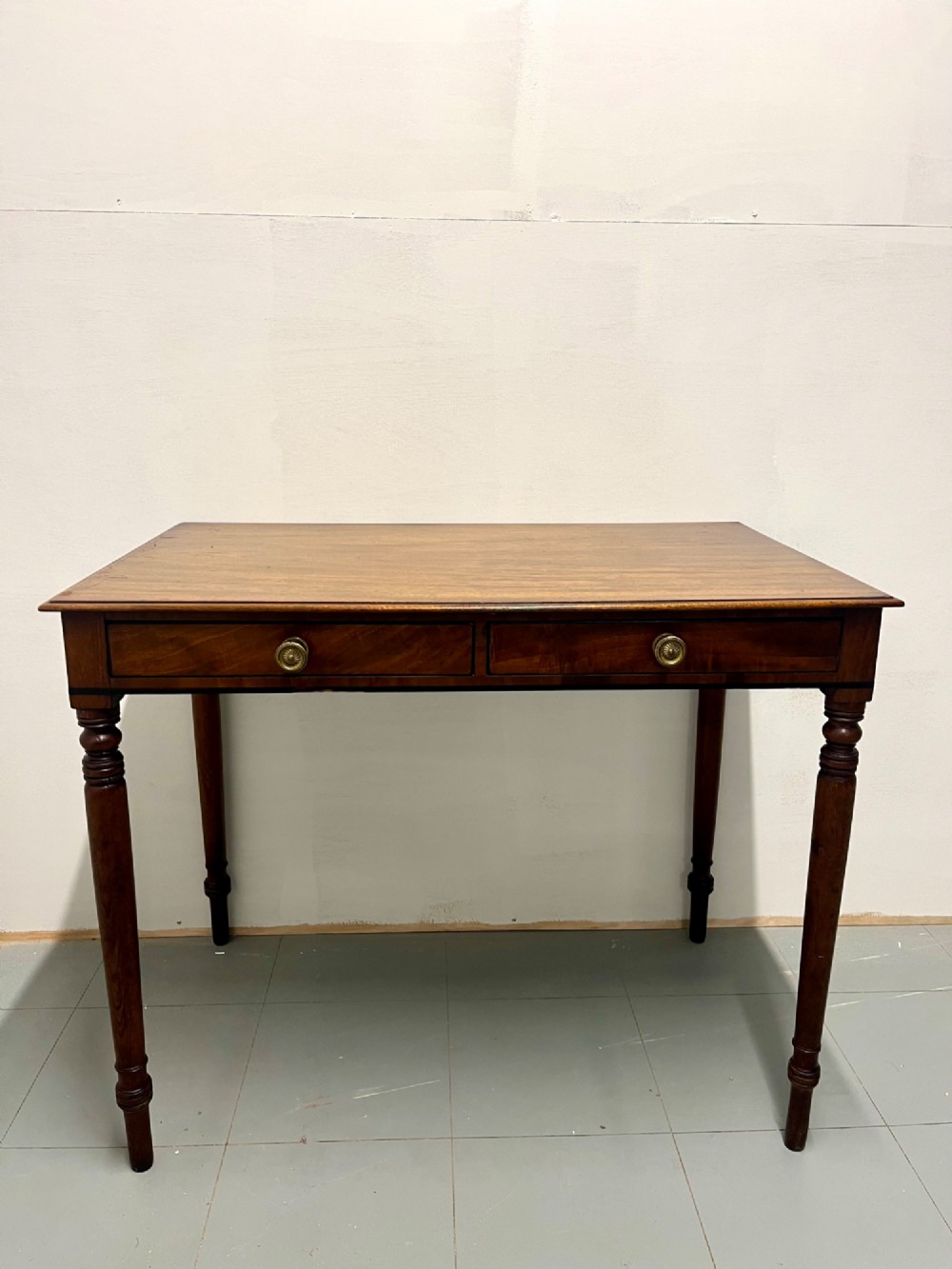 A Scottish Regency mahogany side table featuring two frieze drawers with brass handles and slender turned legs.
