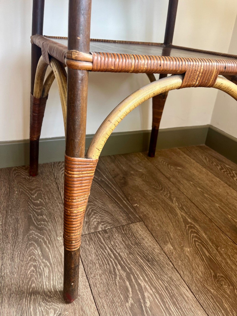 A square two-tier Dryad cane occasional table with a clear glass top, brass corner mounts, dark wood lower shelf, and woven tapered legs. View II