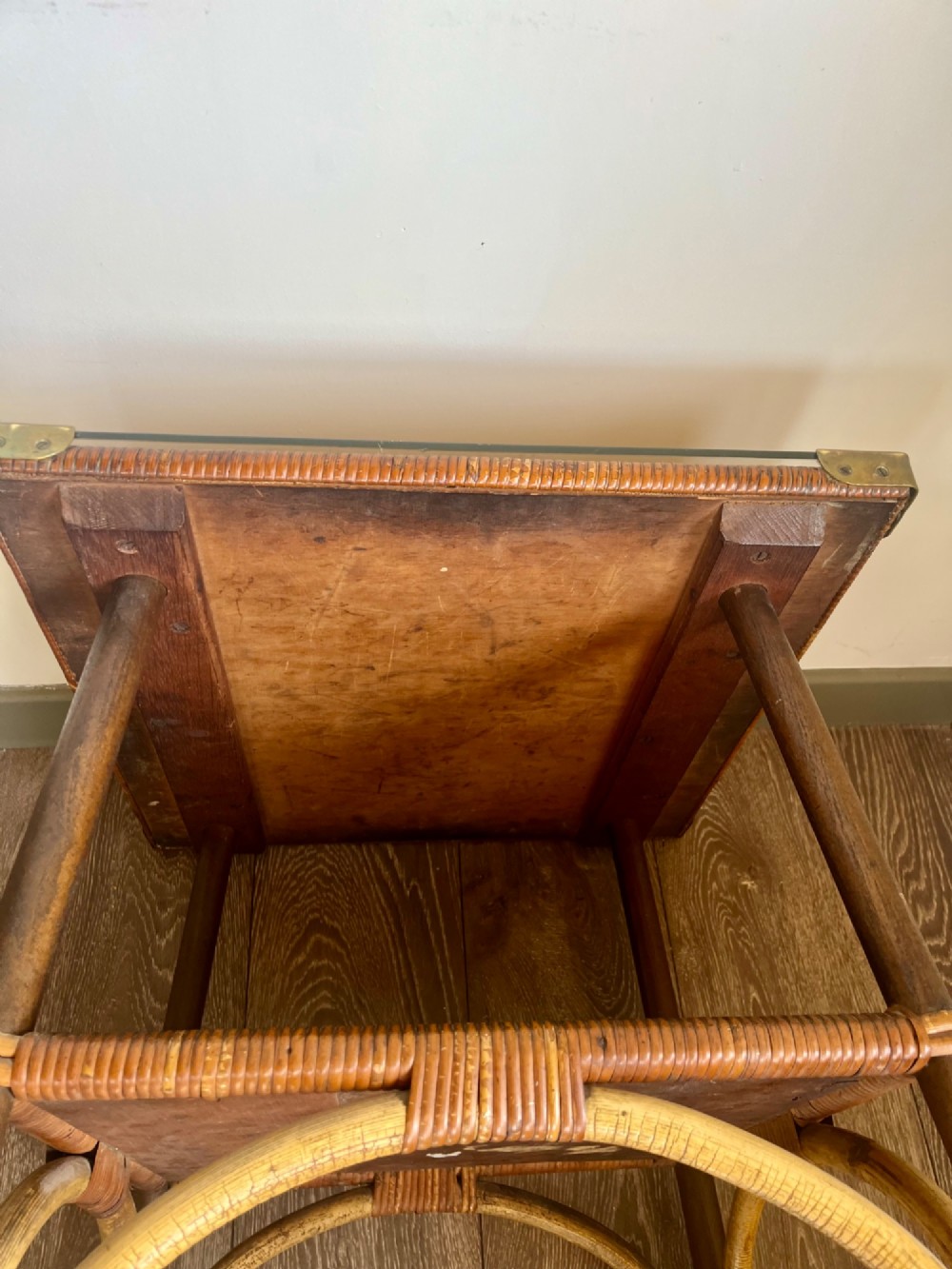 A square two-tier Dryad cane occasional table with a clear glass top, brass corner mounts, dark wood lower shelf, and woven tapered legs. View VIII