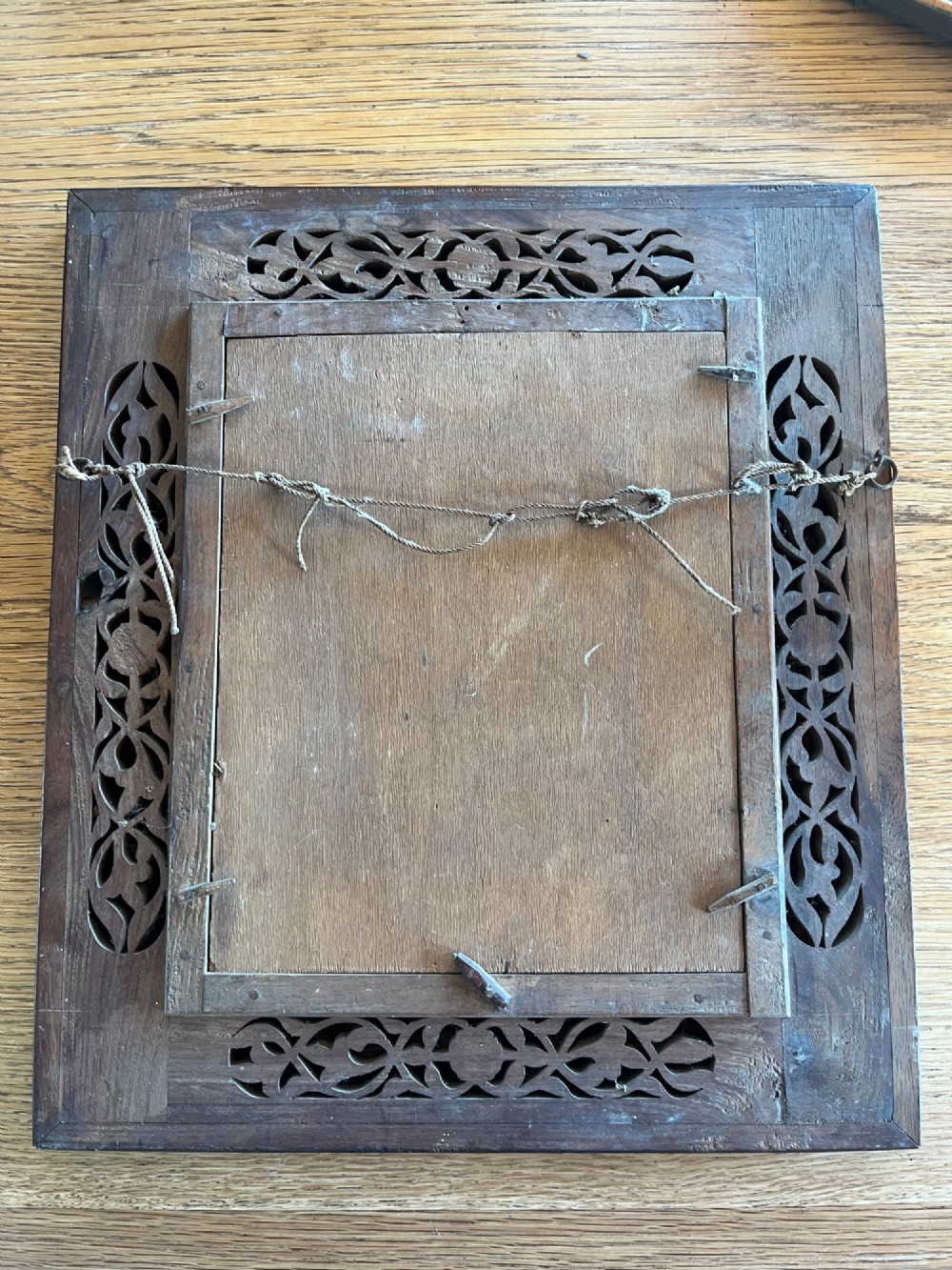 Corner detail of a rectangular dark wood frame decorated with brass foliate inlay and pierced scrollwork panels. View VIII
