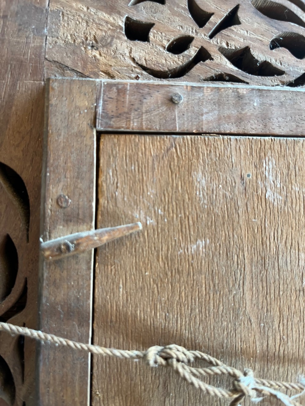 Corner detail of a rectangular dark wood frame decorated with brass foliate inlay and pierced scrollwork panels. View IX
