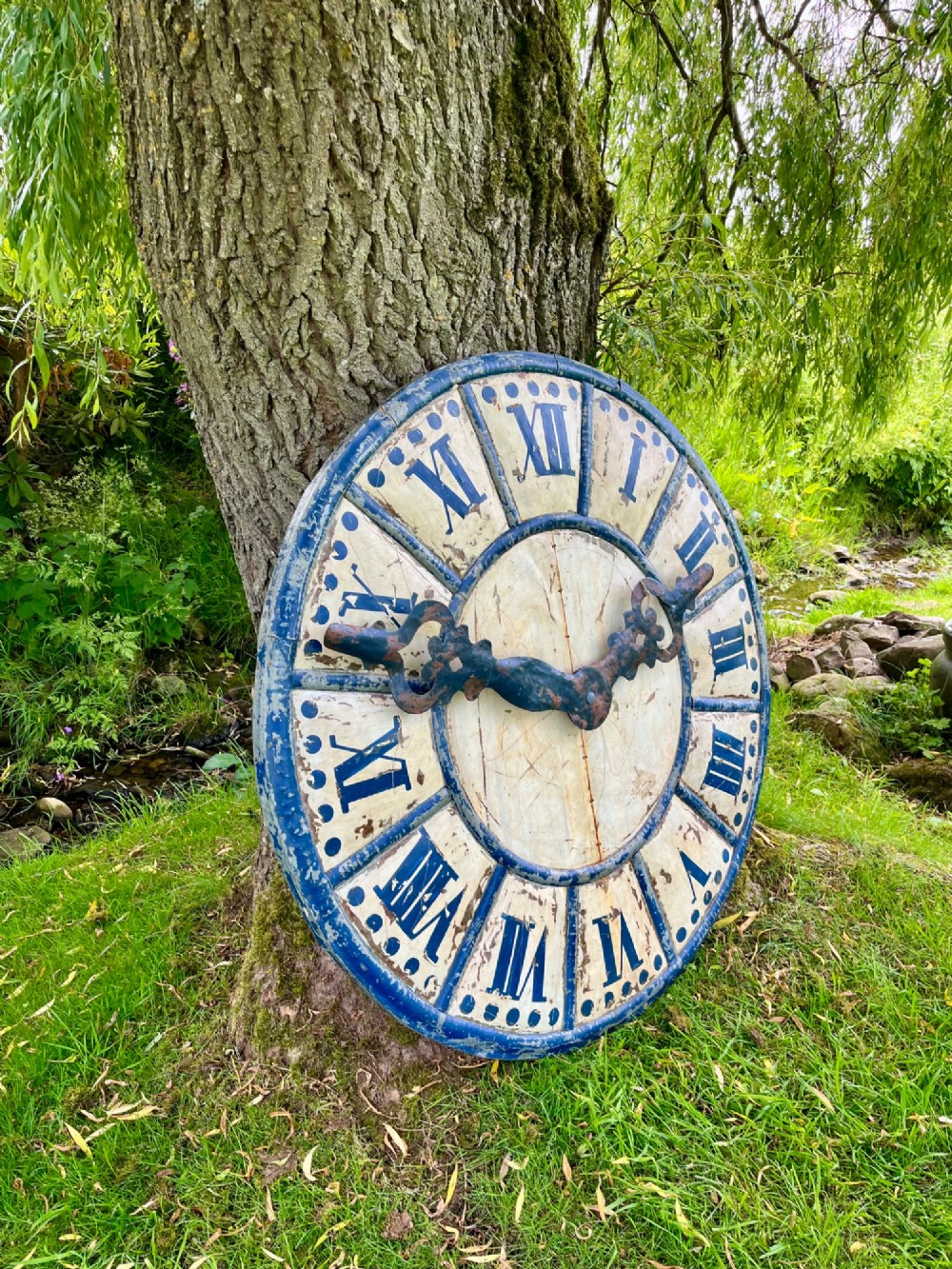 A circular antique French tower clock face with cream and blue painted sections, blue Roman numerals, and decorative wrought iron hands. View II