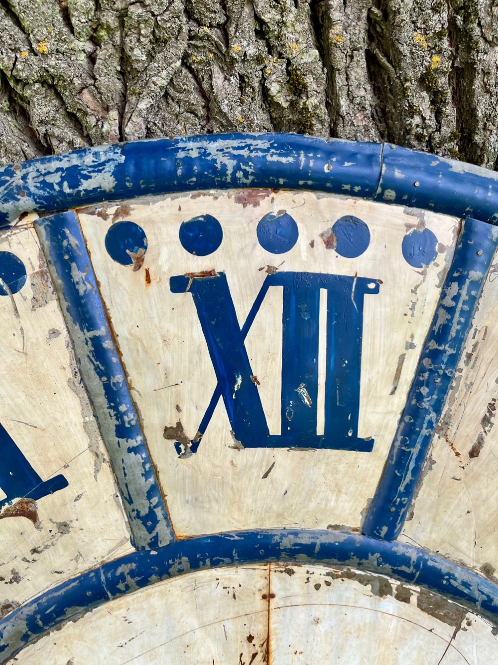 A circular antique French tower clock face with cream and blue painted sections, blue Roman numerals, and decorative wrought iron hands. View III