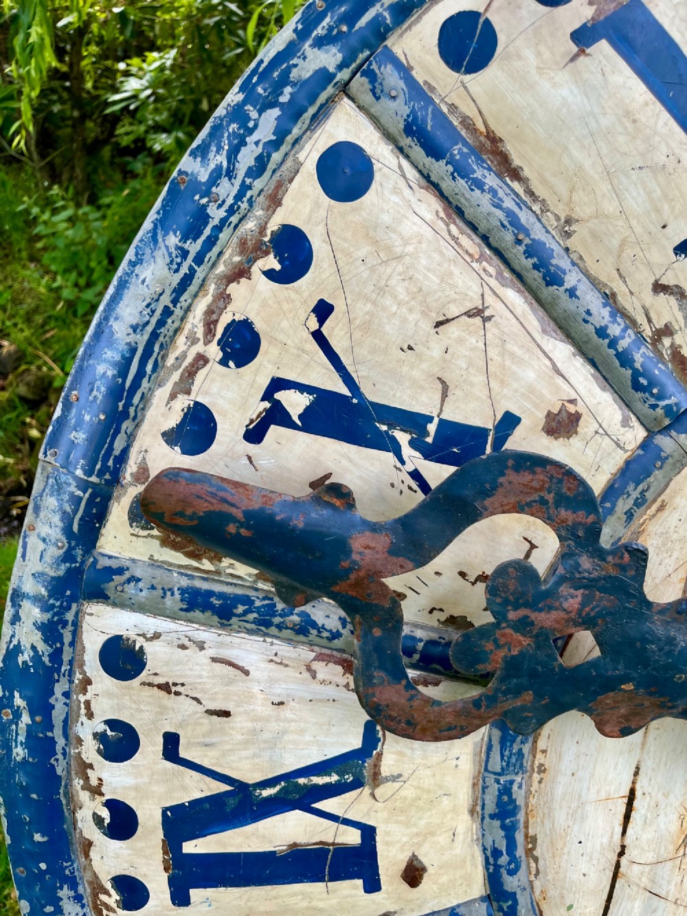 A circular antique French tower clock face with cream and blue painted sections, blue Roman numerals, and decorative wrought iron hands. View IV