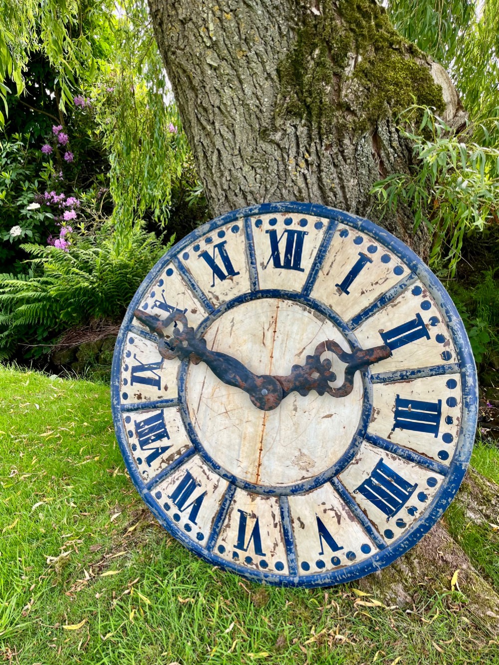 A circular antique French tower clock face with cream and blue painted sections, blue Roman numerals, and decorative wrought iron hands. View VI