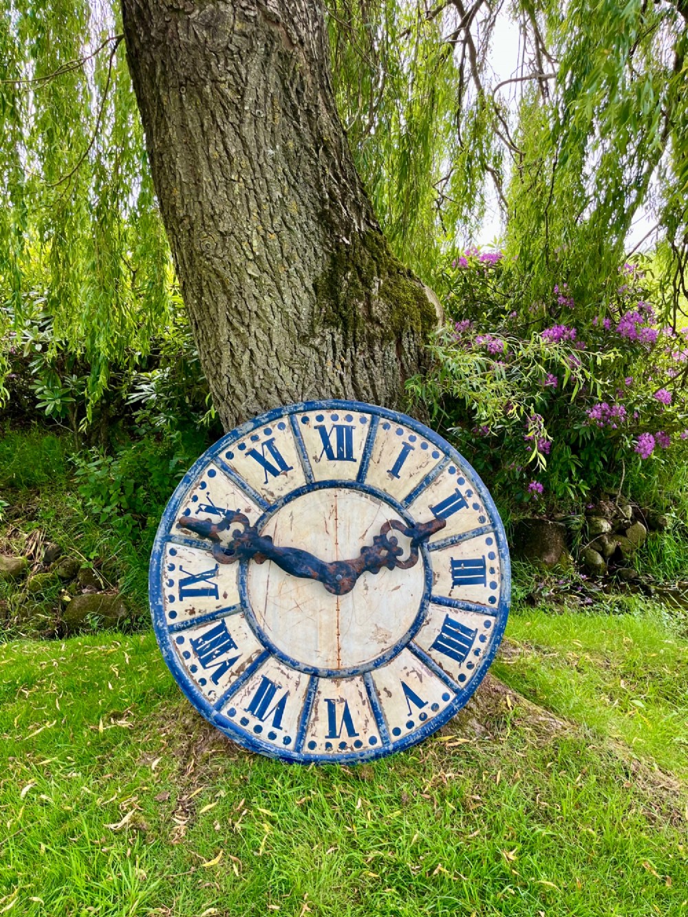 A circular antique French tower clock face with cream and blue painted sections, blue Roman numerals, and decorative wrought iron hands. View IX