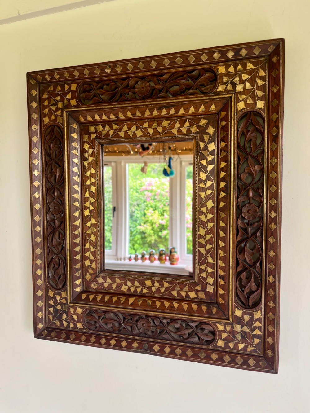Corner detail of a rectangular dark wood frame decorated with brass foliate inlay and pierced scrollwork panels. View X